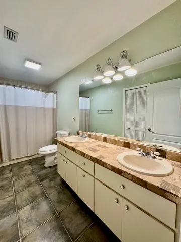 a bathroom with a granite countertop sink a toilet a mirror and shower