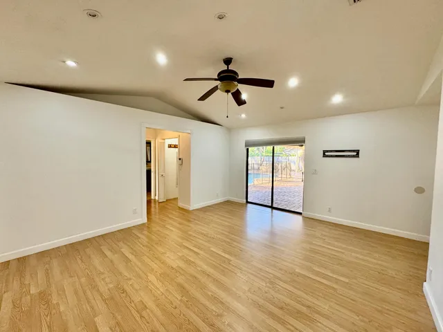 a view of an empty room with window and wooden floor