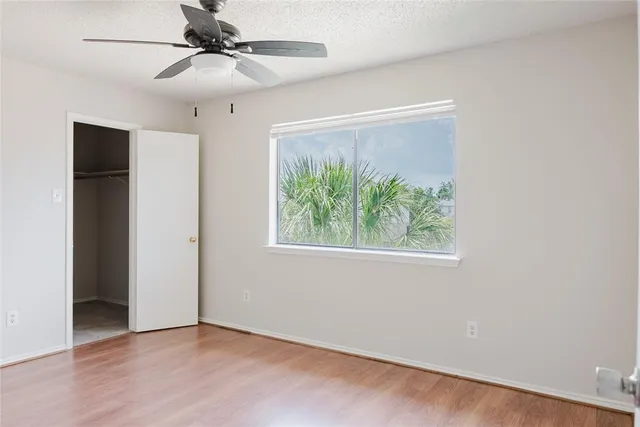 an empty room with a window and a ceiling fan