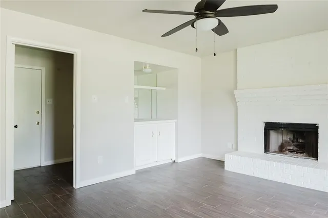 a view of an empty room with wooden floor and a fireplace