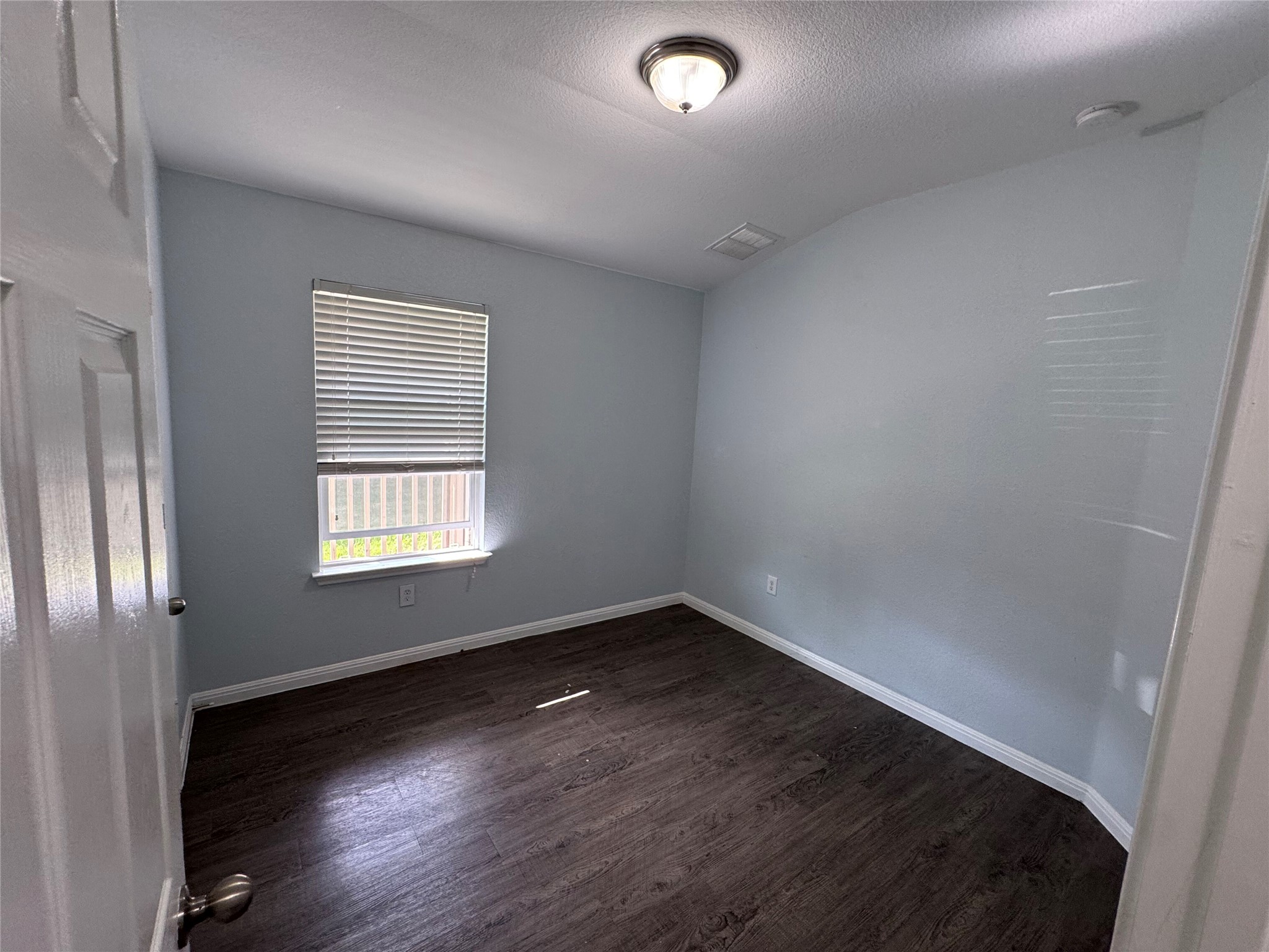 1520 Portchester Castle Path Pflugerville, TX 78660 - Photo 15 of 26 A well-lit room showcasing rich dark wood flooring and a single window with blinds.