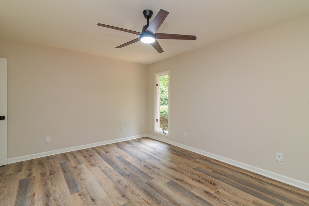 8585 McKee Road Upatoi, GA 31829 - Photo 58 of 62 an empty room with wooden floor ceiling fan and windows