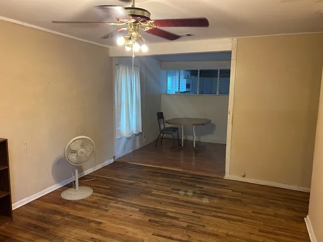 a view of a room with wooden floor fan and windows