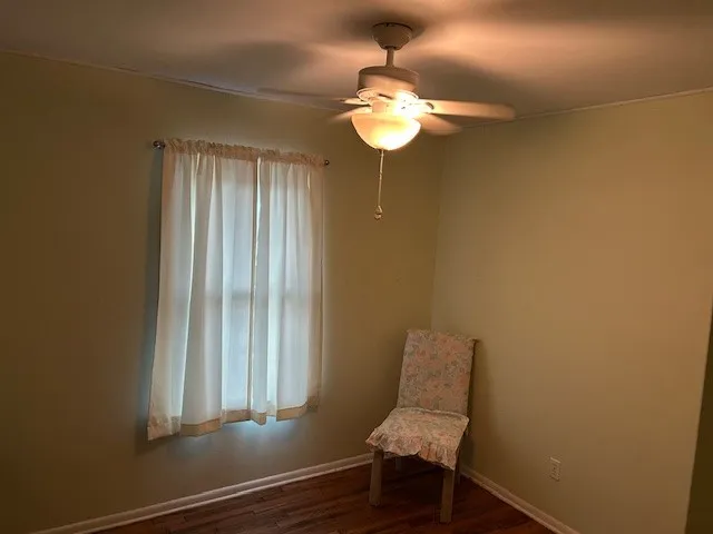 a view of a room with a chandelier fan and wooden floor