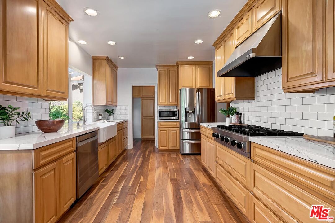 384 North Bonhill Road Los Angeles, CA 90049 - Photo 12 of 32 a kitchen with stainless steel appliances a stove a sink a refrigerator and cabinets