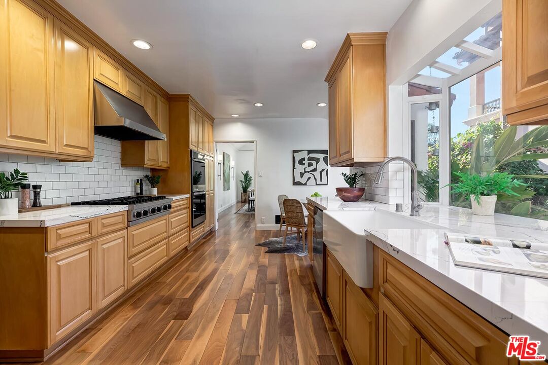 384 North Bonhill Road Los Angeles, CA 90049 - Photo 13 of 32 a kitchen with stainless steel appliances a sink stove and cabinets