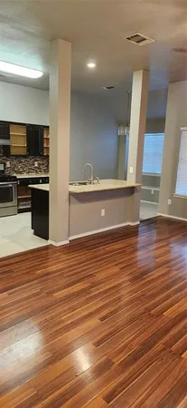 a view of kitchen and empty room with wooden floor