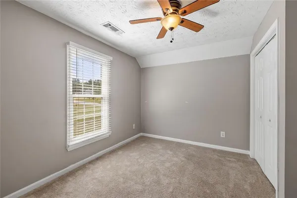 an empty room with windows and chandelier fan