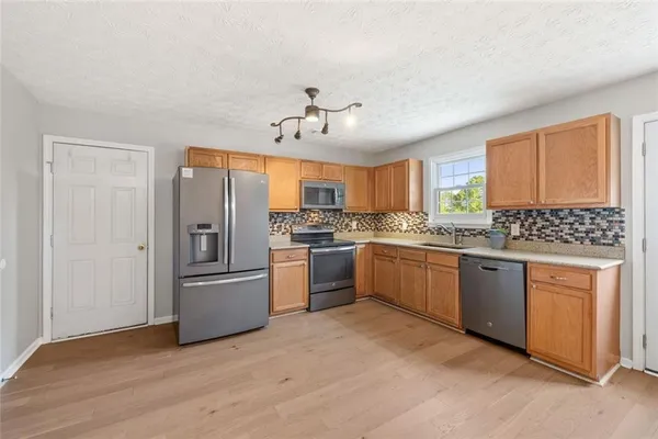 a kitchen with granite countertop a refrigerator and white cabinets