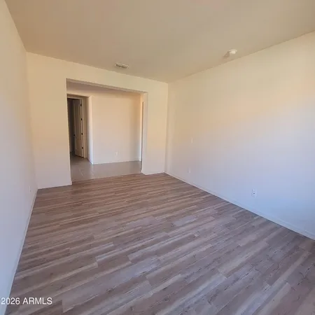 a view of an empty room with wooden floor and closet