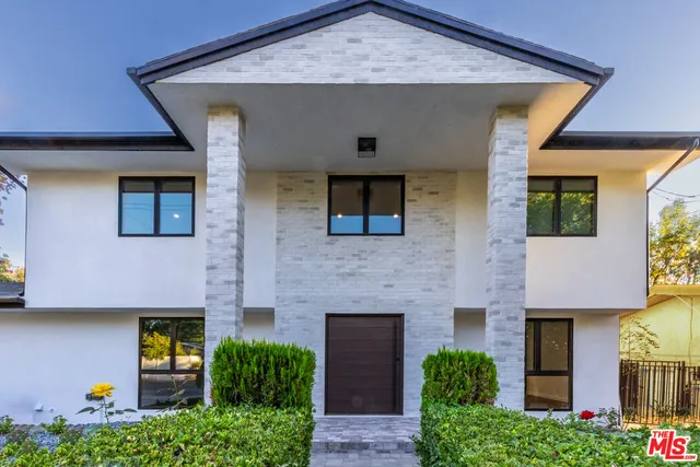 a front view of a house with plants