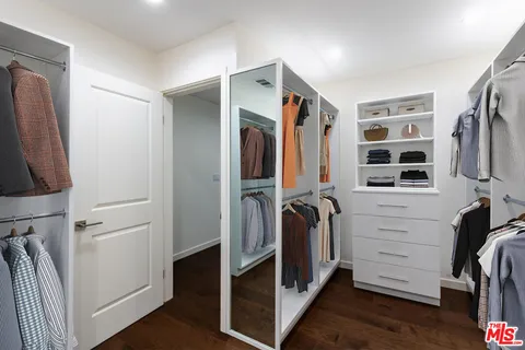 a view of walk in closet with clothes and shoes