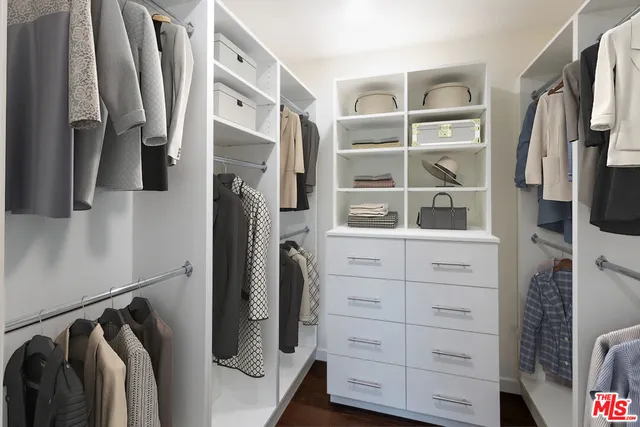 a view of walk in closet with clothes and shoes