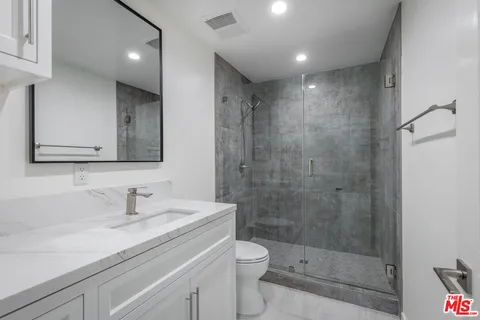 a bathroom with a shower sink vanity mirror and toilet
