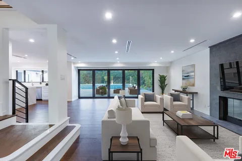 a living room with furniture fireplace and large windows