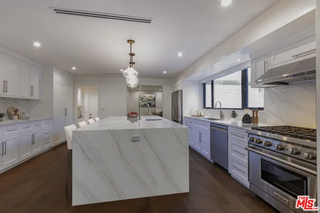 a large kitchen with kitchen island a stove a sink dishwasher and a oven with wooden floor