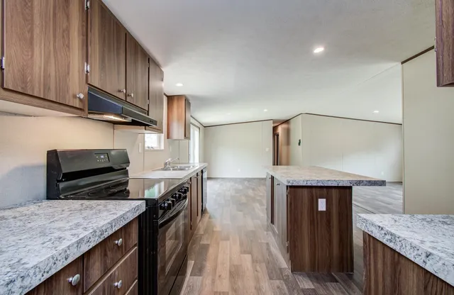 a kitchen with granite countertop a stove top oven and cabinets
