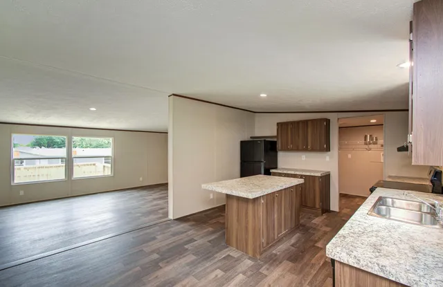 a large kitchen with a refrigerator a sink dishwasher and a stove with wooden floor