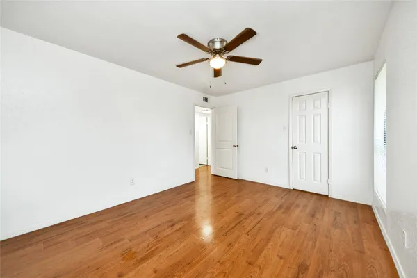 an empty room with wooden floor and ceiling fan