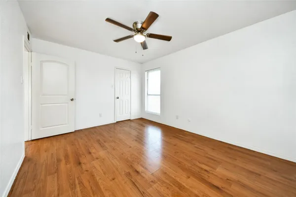 an empty room with wooden floor and ceiling fan
