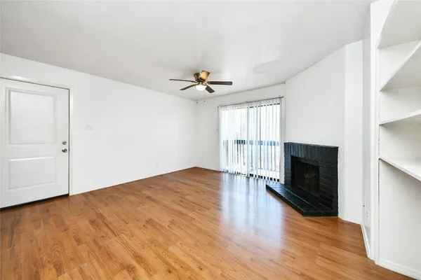 an empty room with wooden floor fireplace and windows