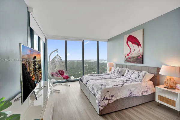a living room with couch a flat screen tv and a floor to ceiling window
