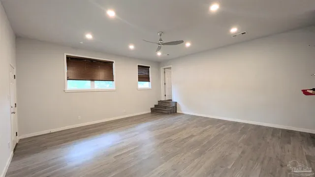 an empty room with wooden floor and windows