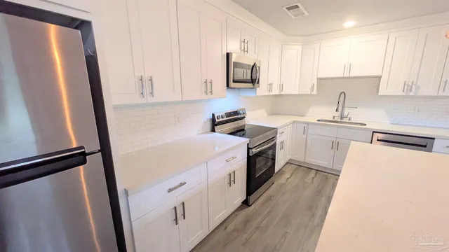 a kitchen with stainless steel appliances a sink a stove a refrigerator a window