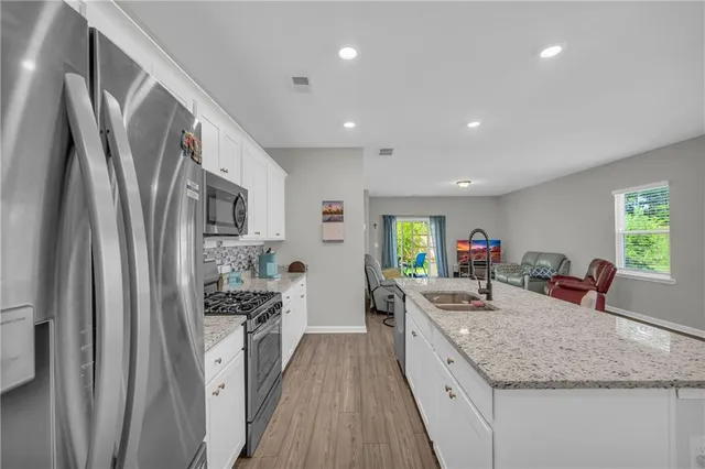 a kitchen with stainless steel appliances granite countertop a sink stove and cabinets