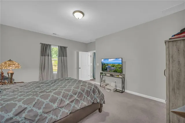 a bedroom with a bed and a flat tv screen on dresser