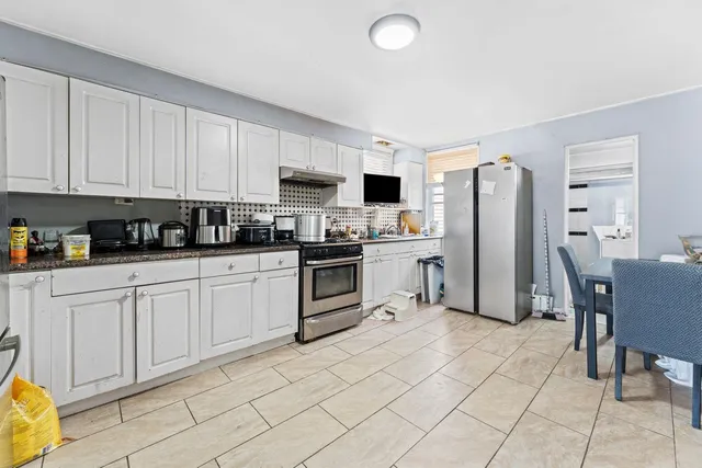 a kitchen with a refrigerator a stove a sink a dining table and chairs