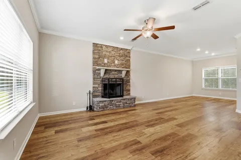a view of an empty room with wooden floor fireplace and a window