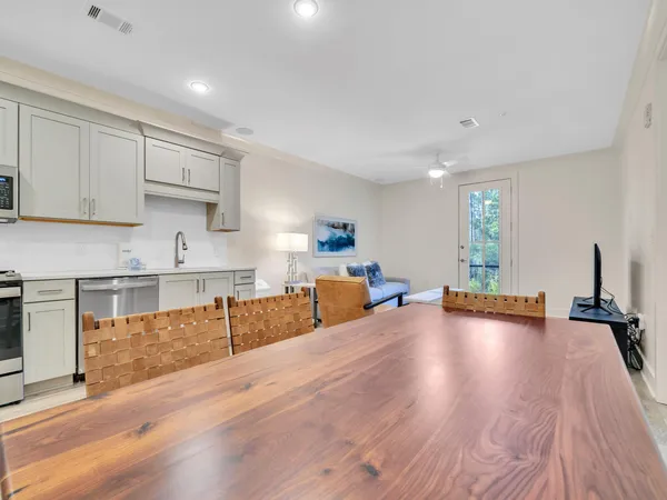 a view of a kitchen with kitchen island a sink wooden floor and black appliances