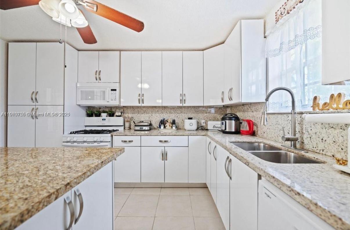 20235 Southwest 172nd Avenue Miami, FL 33187 - Photo 20 of 30 a kitchen with stainless steel appliances granite countertop a sink dishwasher and white cabinets with wooden floor