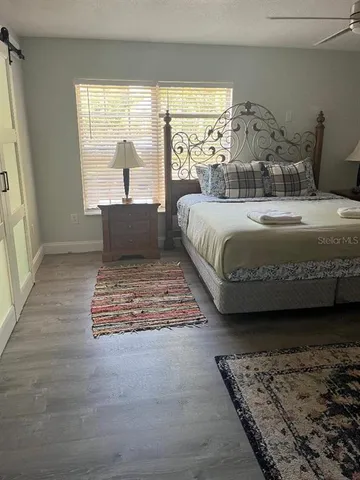 a bedroom with a bed lamp and a large window