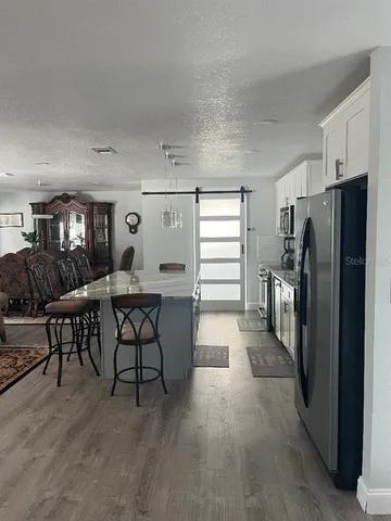 a living room with furniture a large window and stainless steel appliances