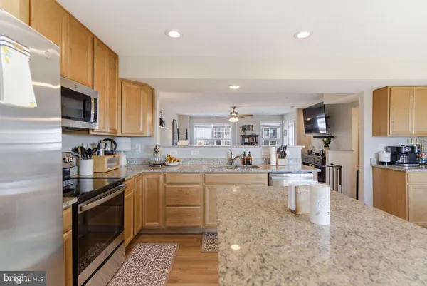 a kitchen with stainless steel appliances granite countertop a stove top oven a sink a dining table and chairs