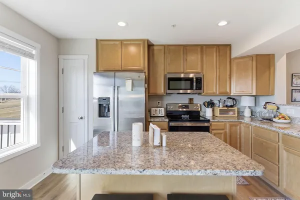 a kitchen with stainless steel appliances granite countertop a stove a refrigerator a sink a microwave and island