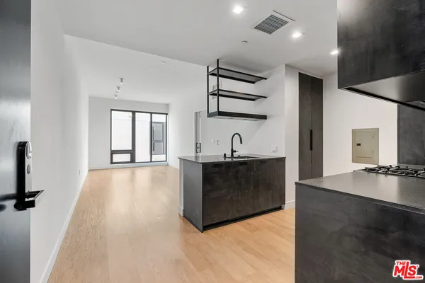 a living room with stainless steel appliances kitchen island a large counter top and a wooden floor
