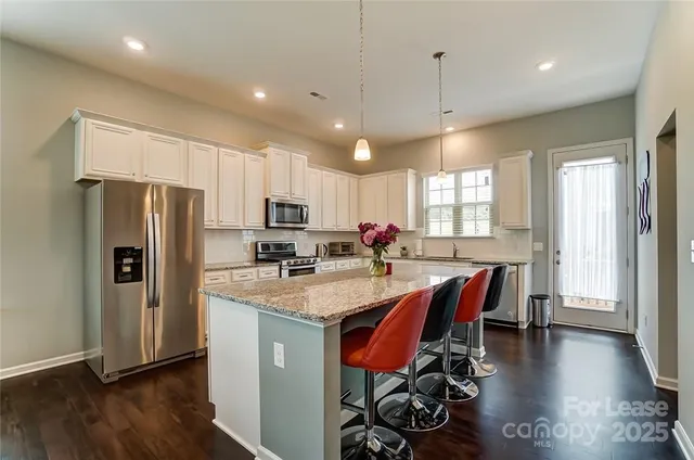 a kitchen with stainless steel appliances granite countertop a refrigerator a sink dishwasher a stove and a refrigerator with wooden floor