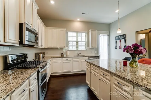 a kitchen with stainless steel appliances granite countertop a sink stove and cabinets
