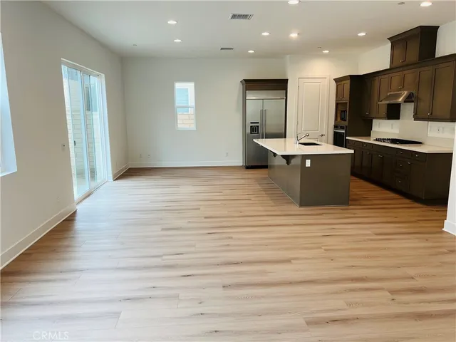 a view of kitchen with stainless steel appliances kitchen island wooden cabinets and fireplace
