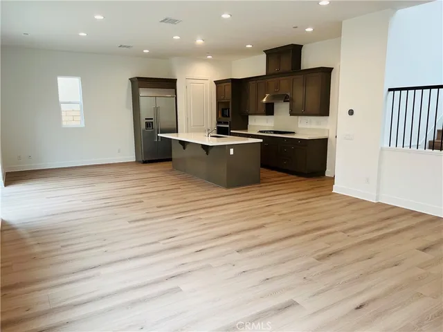 a large kitchen with kitchen island a sink dishwasher a stove and a refrigerator with wooden floor