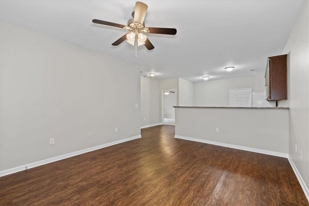 150 Old Mill Road, Unit 435 Cartersville, GA 30120 - Photo 8 of 22 an empty room with wooden floor a ceiling fan and kitchen view