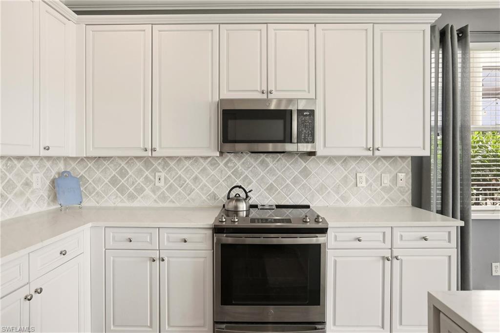 2150 Khasia Point Naples, FL 34119 - Photo 11 of 42 a kitchen with granite countertop white cabinets and a stove