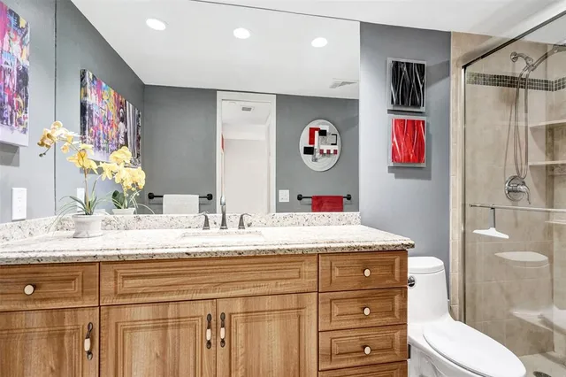 a bathroom with a granite countertop sink mirror vanity and toilet