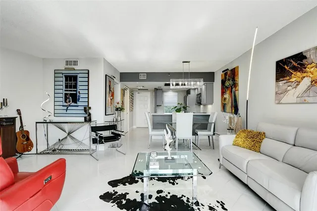 a living room with furniture large window and kitchen view