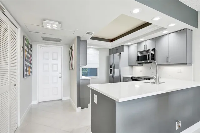 a large kitchen with a sink stainless steel appliances and cabinets