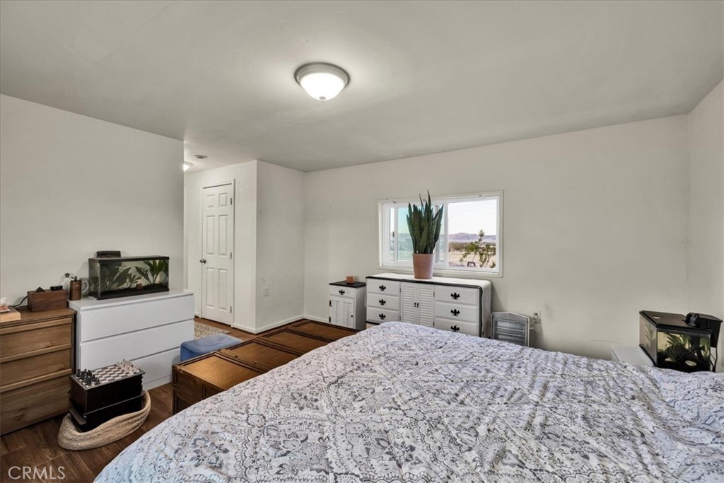 67550 Del Oro Road Twentynine Palms, CA 92277 - Photo 15 of 41 a bedroom with a bed and wooden floor