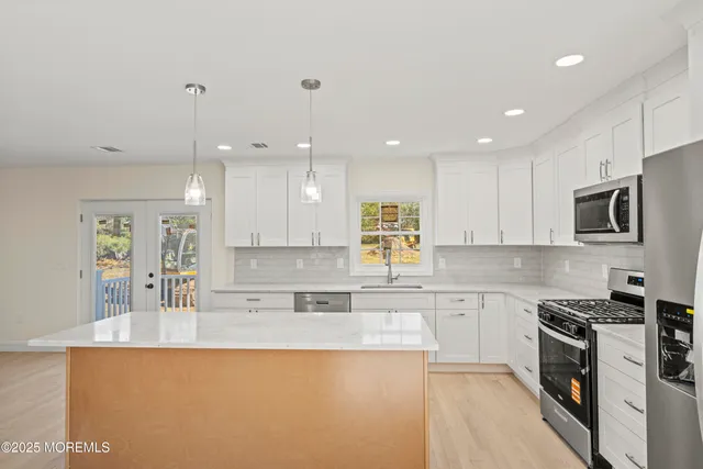 a kitchen with stainless steel appliances granite countertop a sink a stove a refrigerator and island with wooden floor